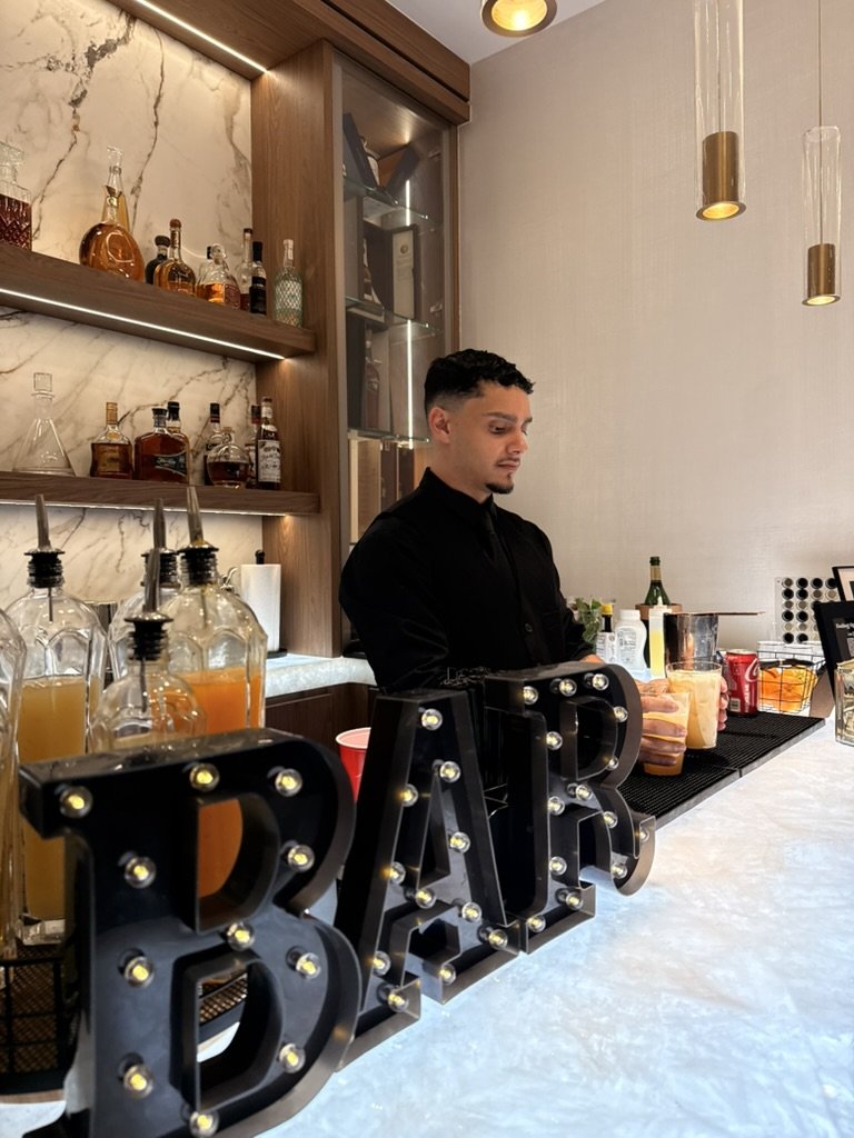 Rey working behind marquee BAR letters at a marble home bar