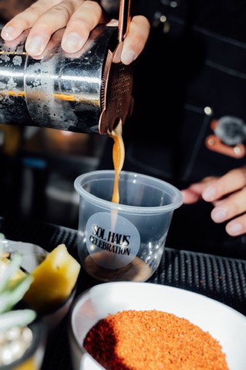 Straining a cocktail into a custom Sol Haus Celebration cup
